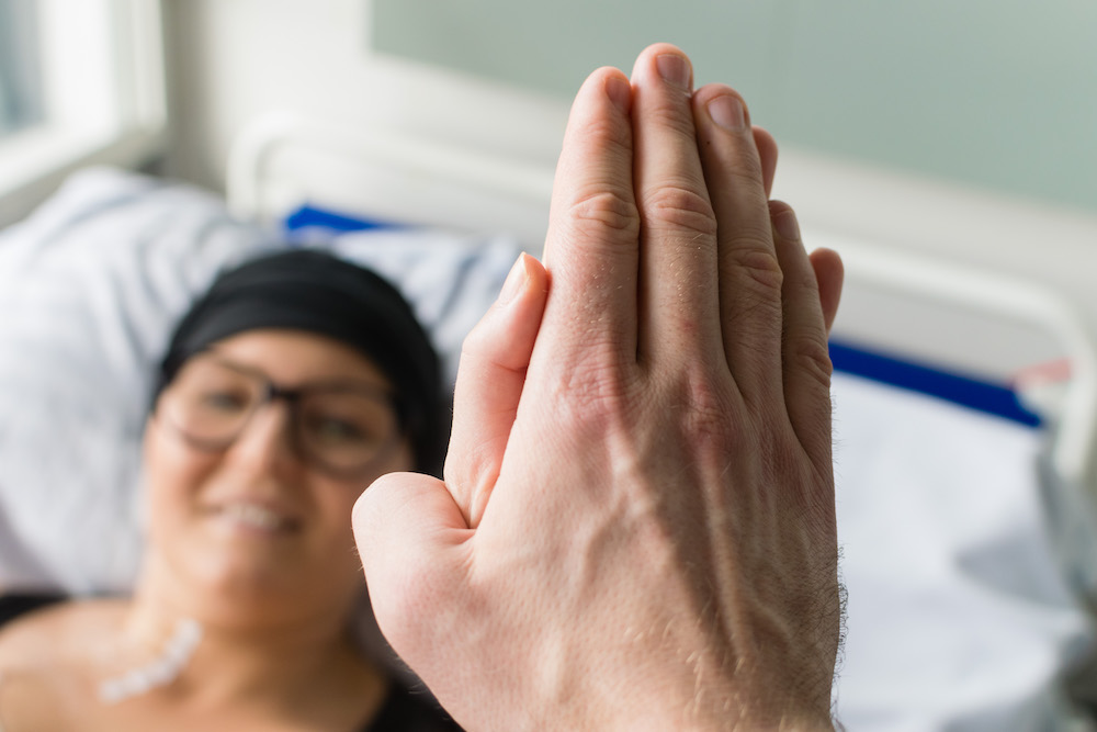 photo of person in hospital bed high-fiving a visitor